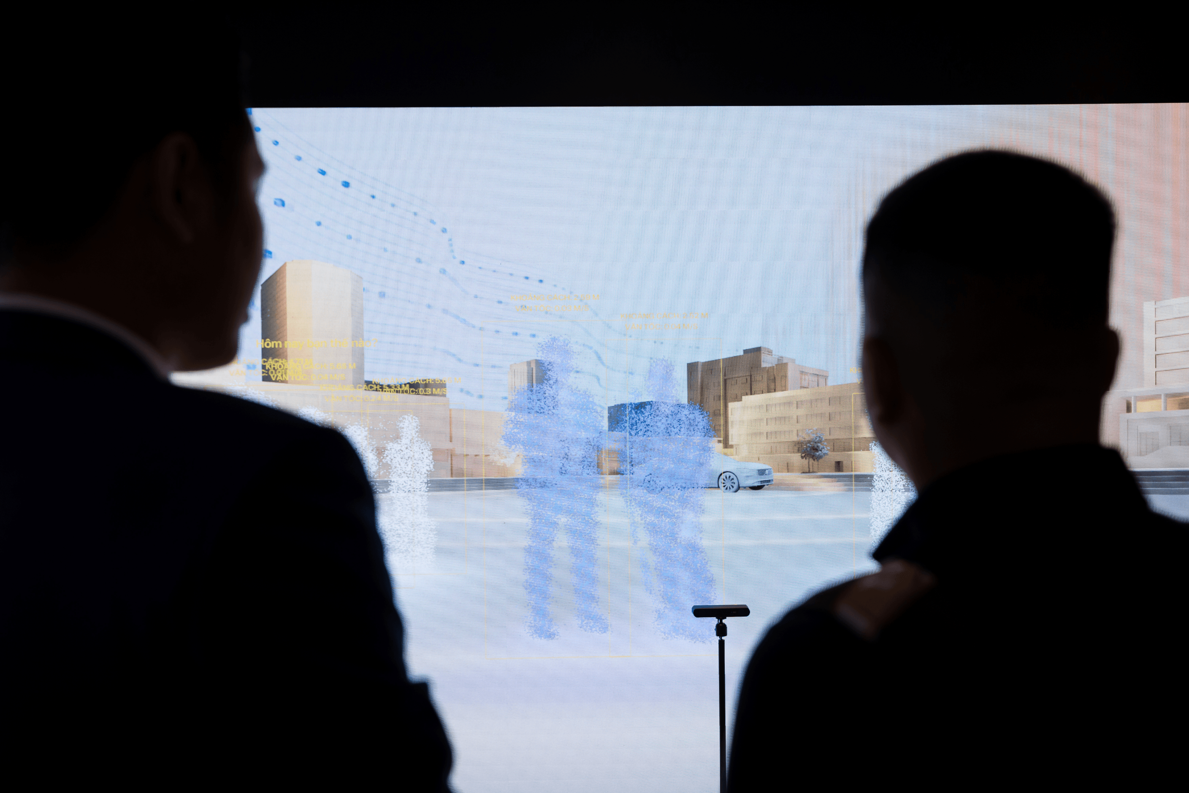 Two male visitors observing a real-time pedestrian detection installation on a large-scale display