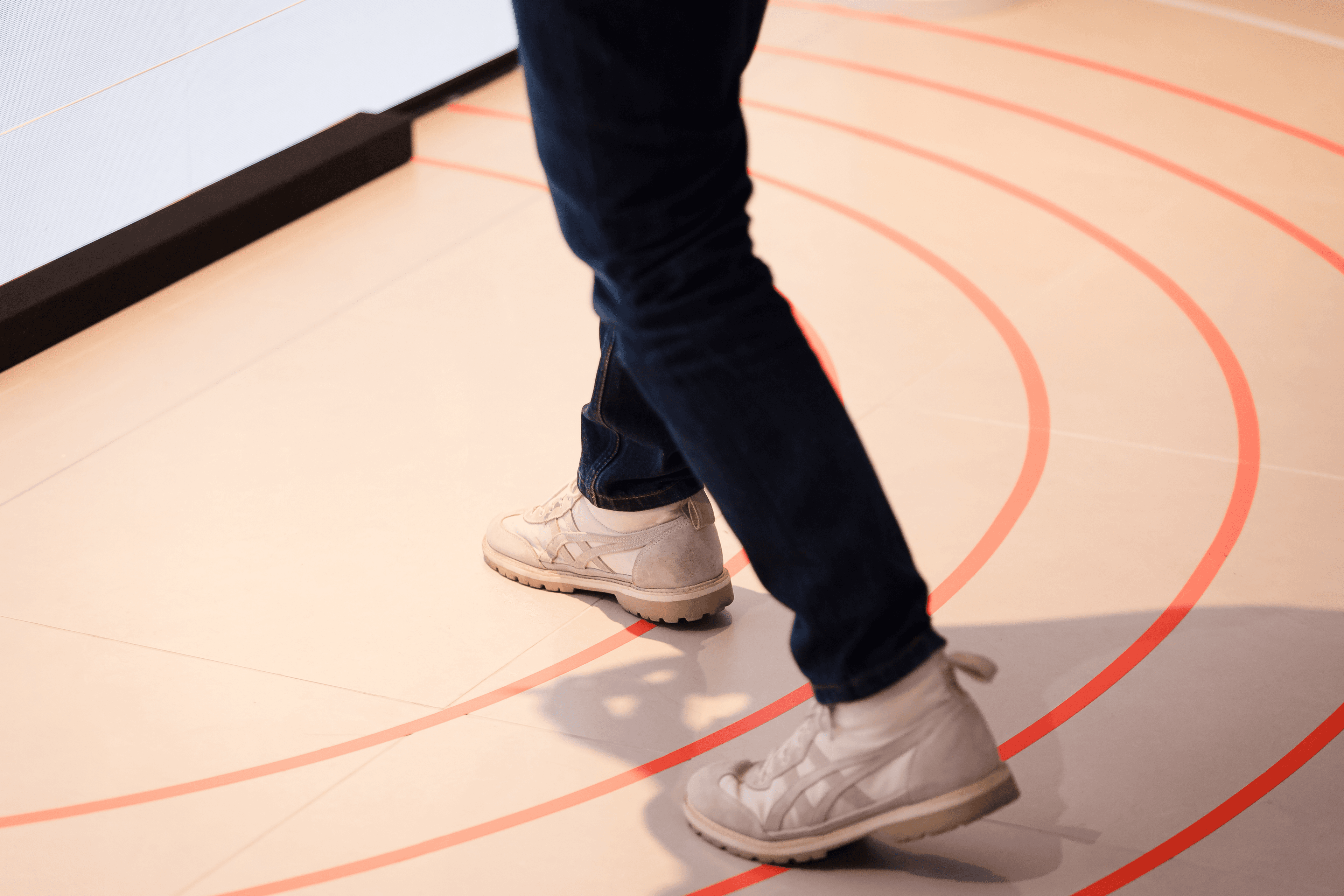 Close-up of a visitor's feet stepping across the interactive sensor floor with red concentric circles in the installation