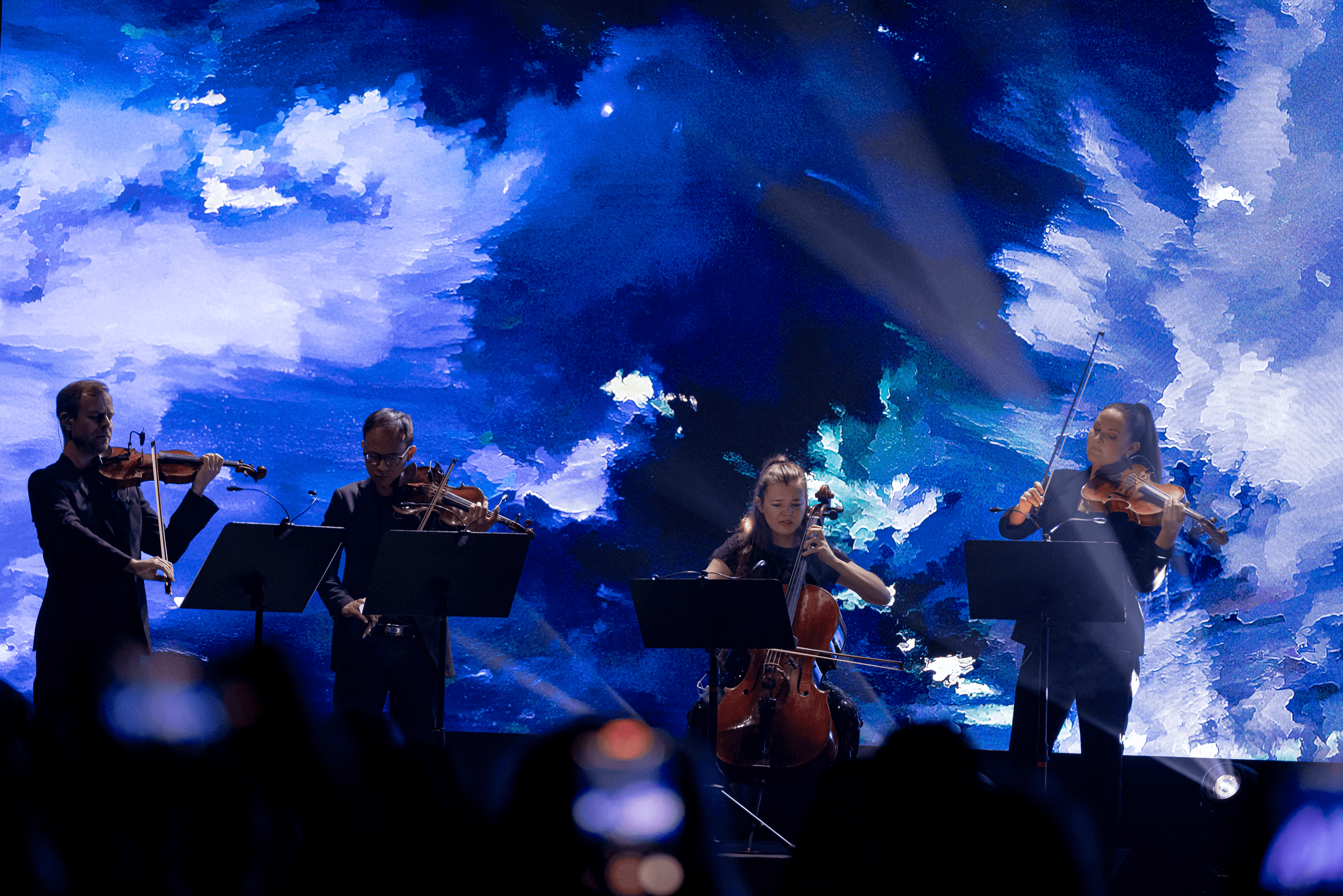 Detail of the live performance at the AI For Good Summit 2025. Mid-shot of four string musicians performing in front of a full-width LED screen.