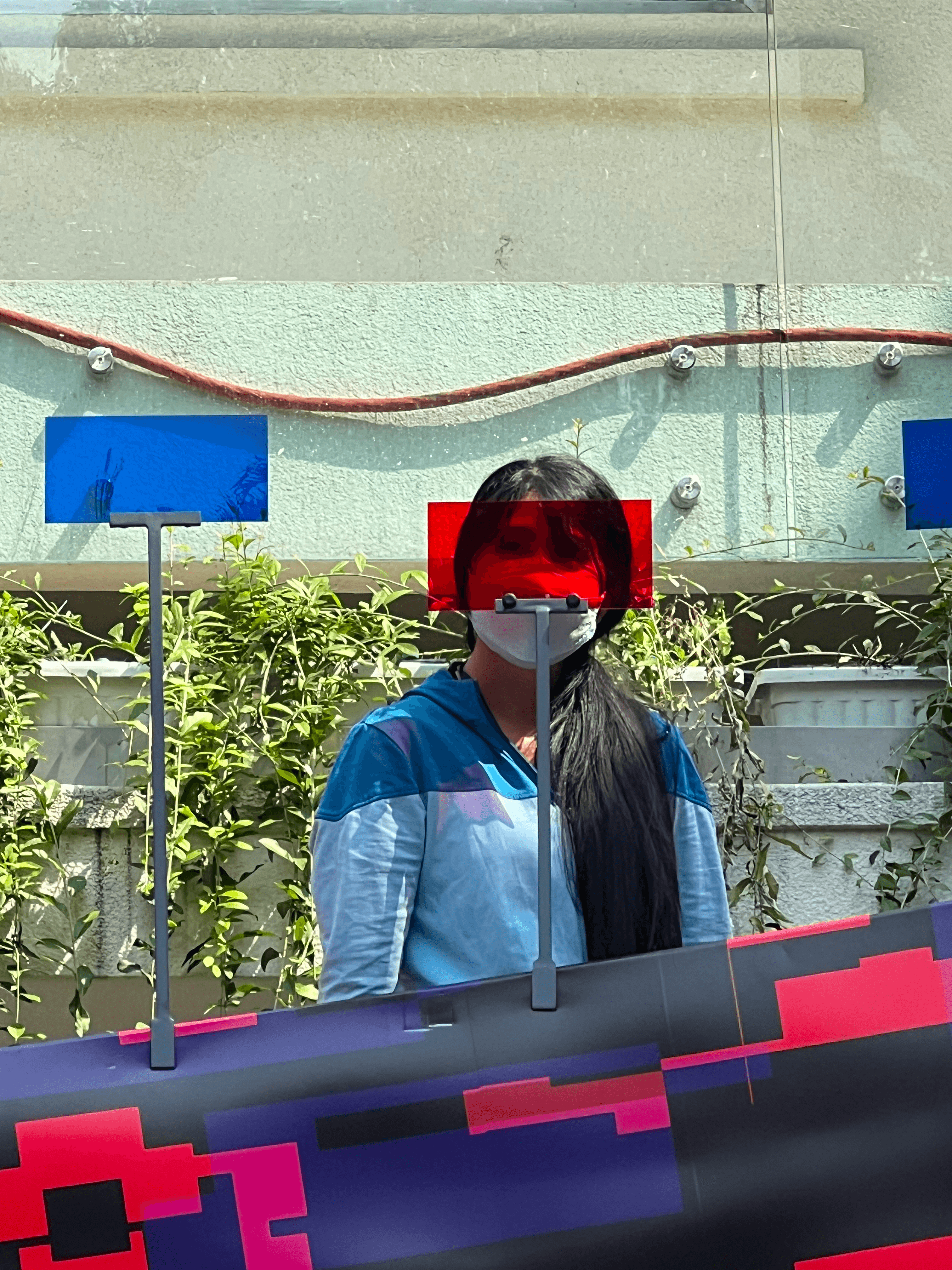 A visitor seen through red and blue acrylic panels at the 'Đủ' exhibition outdoor installation