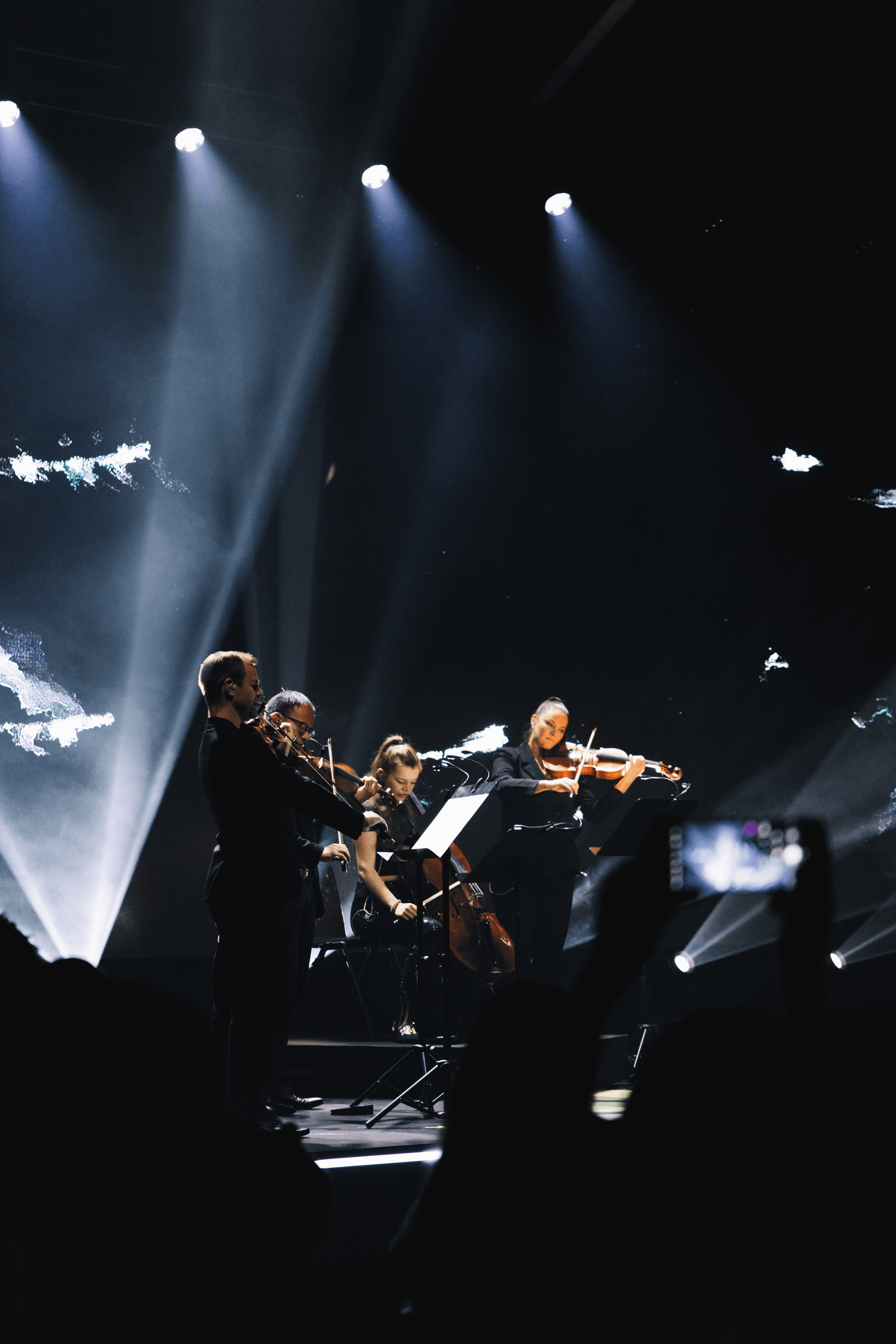 Installation view of the string quartet performance at the AI For Good Summit 2025. Four musicians in black perform on the stage. Vertical mid-shot from a low angle, taken from within the audience.