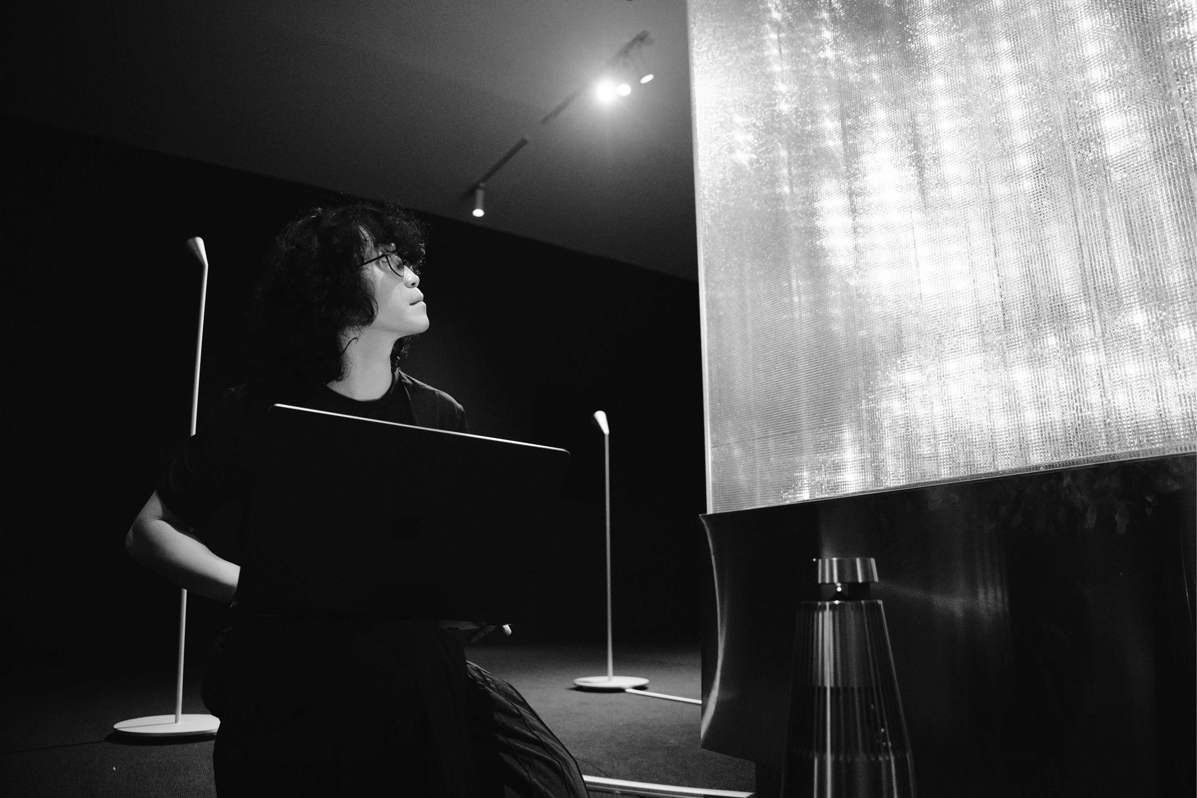 Fustic.’s Creative Director adjusts the system from a laptop in the exhibition room, looking up toward the installation.