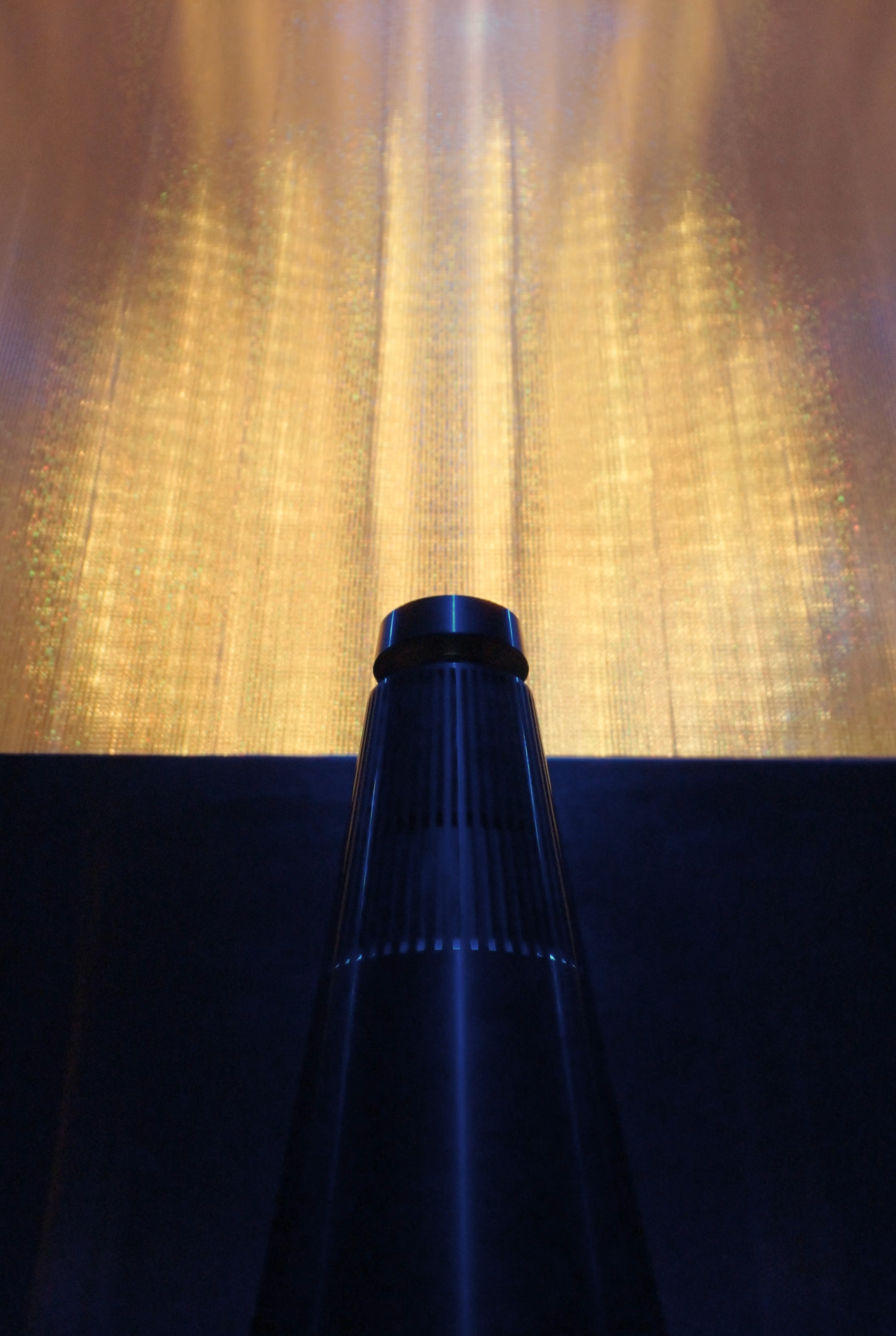 A close-up of the top of the Bang & Olufsen Beosound speaker standing in front of the installation.