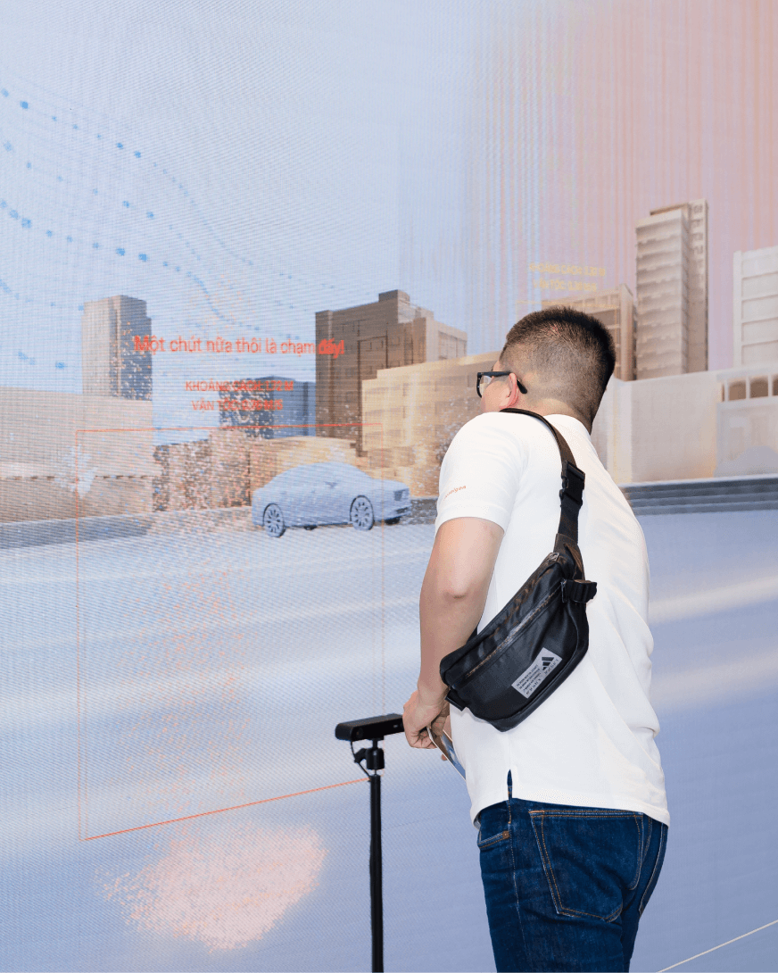 A visitor interacts with the human-detection sensor while viewing the collision-warning simulation on a large LED display