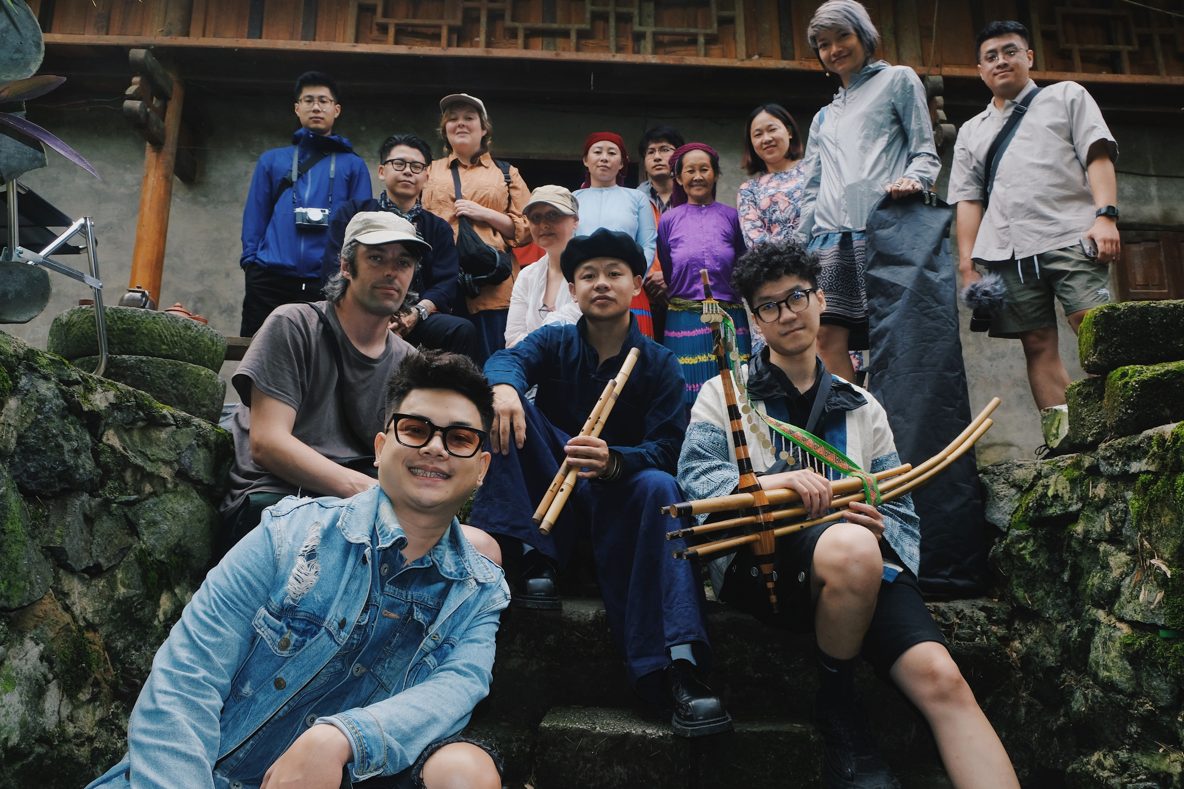 The project team poses together on stone steps outside a traditional house in Ha Giang. The group includes artists, local community members and visiting researchers.