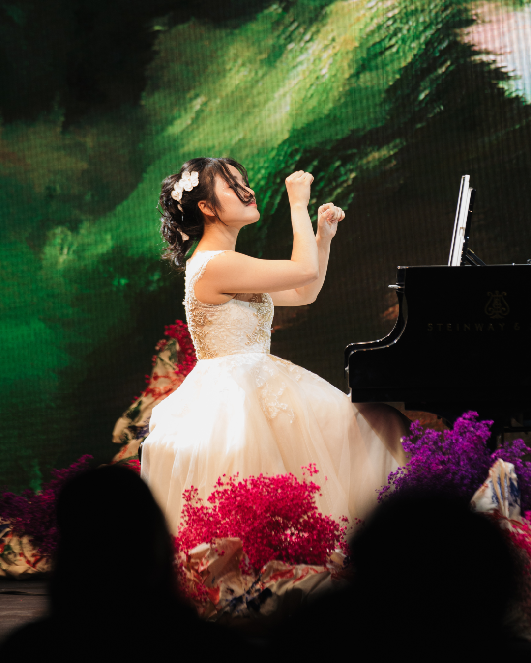 The pianist Ngô Phương Vi at a grand piano, captured with hands lifted, against a green abstract generative background.