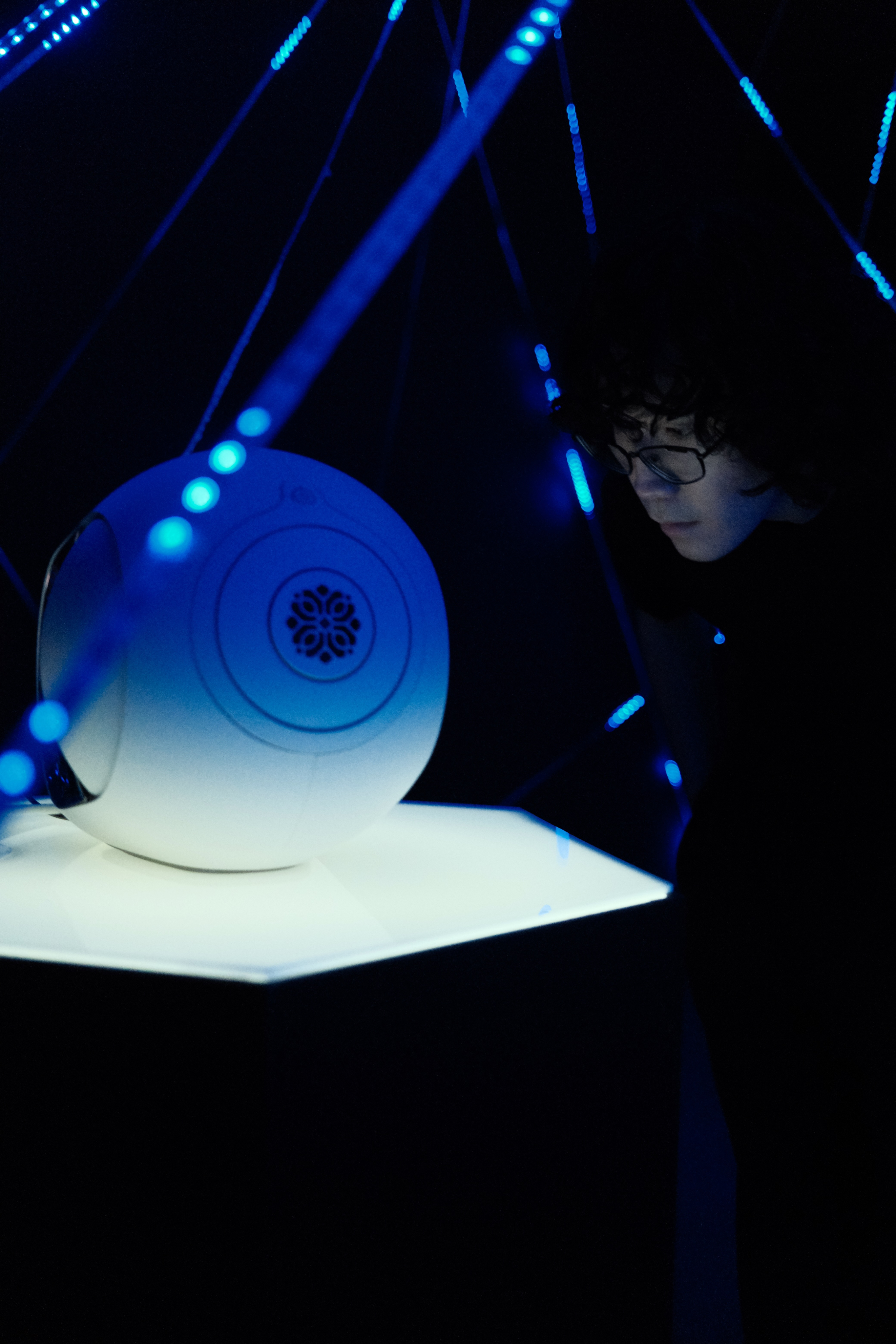 A man leans in to closely examine the speaker inside the installation
