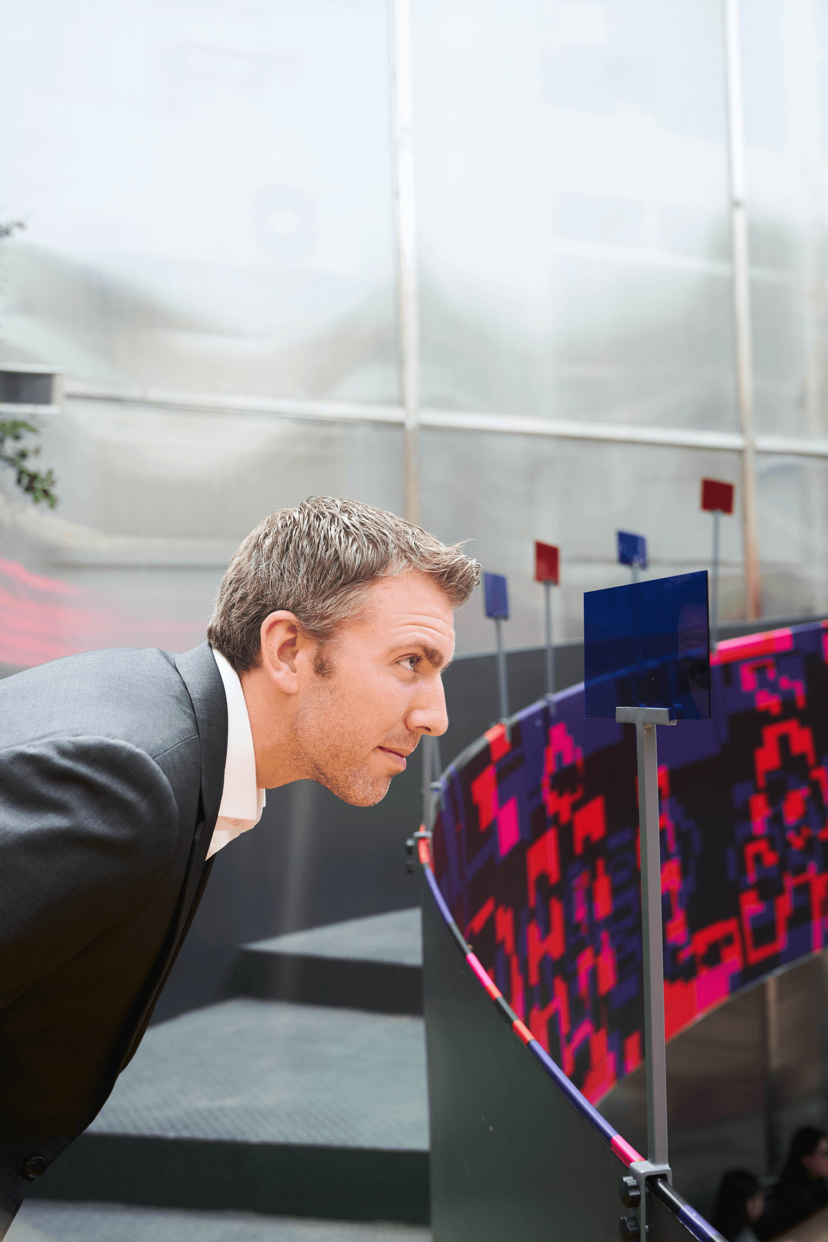 A visitor leaning in to closely examine a colorful acrylic panels sculpture at the 'Đủ' exhibition outdoor installation